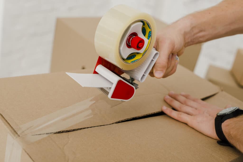 Application d'un adhésif d'emballage avec dévidoir pour la fermeture carton
